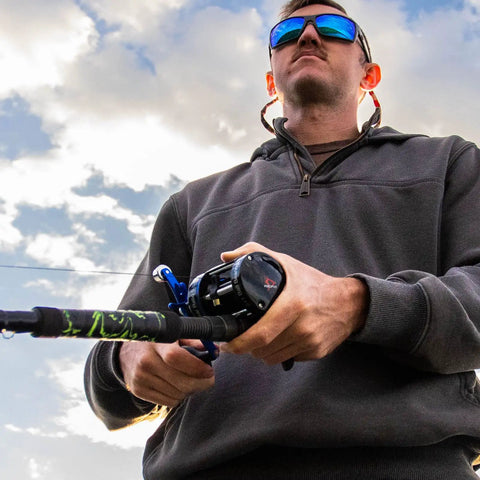 Angler holding Chaos XS Round Baitcasting Reel For Saltwater Inshore Surf Trolling And Catfish Beefy Yet Smooth Conventional Reel