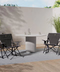 Two Kickback Rocker Outdoor Low Profile Rocking Chairs With Cup Holder And Portable Carry Strap on a patio with a table.