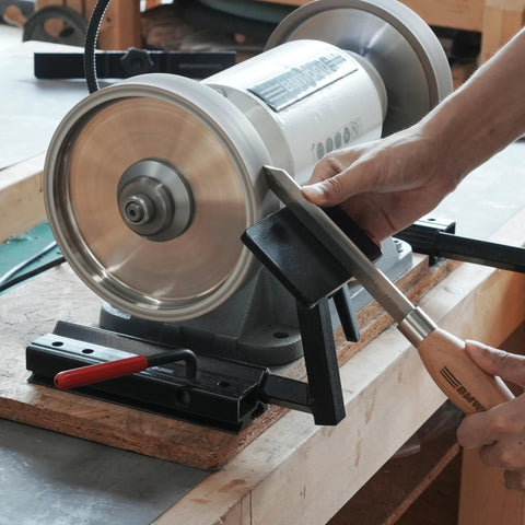 BG-GRIND4 4-piece grinding jig set installed on a bench grinder; wood chisel being sharpened.