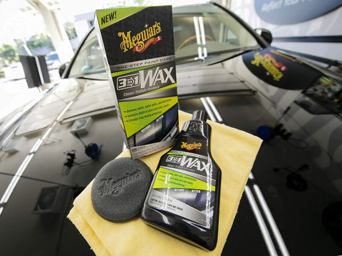 All In One Car Wax Cleaner That Cleans Dirt Grime And Water Spots, bottle and box on top of a polished black car hood, with pad and cloth