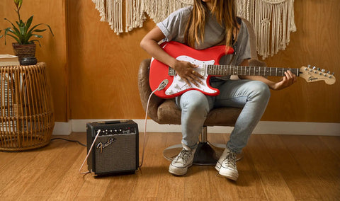 Person playing guitar with Frontman 10G 10 Watt Electric Guitar Amplifier With 6 Inch Speaker in a cozy room