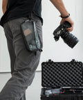 Person holding camera with Neo Zipper Gear Organizer Bag For Electronics And Cameras Cable Organizer Pouch attached to pants.