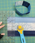 45mm Quick Change Rotary Cutter with Blade Cover on quilt fabric with ruler and spare guard, ultra sharp tungsten blade, aqua handle.
