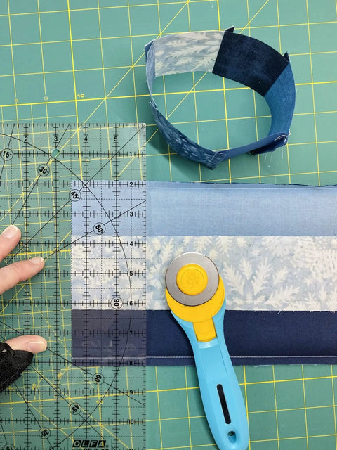 45mm Quick Change Rotary Cutter with Blade Cover on quilt fabric with ruler and spare guard, ultra sharp tungsten blade, aqua handle.