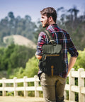 Man with premium three bottle insulated wine carrier featuring engraved cheese board, precision knife, and reliable corkscrew in matte black.