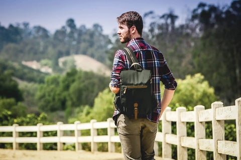 Man with premium three bottle insulated wine carrier featuring engraved cheese board, precision knife, and reliable corkscrew in matte black.