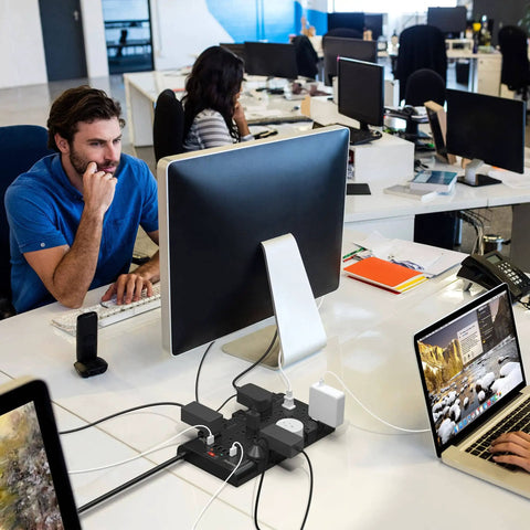 Beefed-Up 28-In-One Power Strip With 22 Outlets And 6 USB Ports, 1875W Surge Protector on an office desk powering devices.
