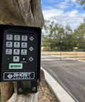 Premium Wireless Keypad For Automatic Gate Openers AXWK Model mounted on a wooden post, road in background