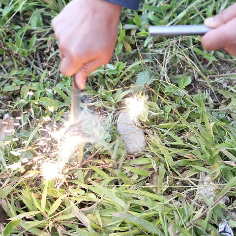 Hands using Extra Large Half Inch By Six Inch Ferro Rod Survival Fire Starter Ferrocerium with sparks on grass