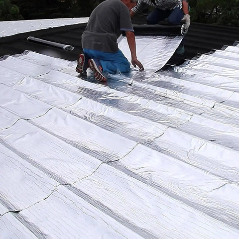 Two workers applying Workhorse Aluminum Foil Roof Patch Tape Self Adhesive Leak Seal Roll on a roof surface.