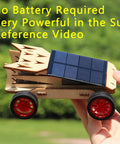 Hand holding solar car from Rockin Build It Solar Car and Remote Control Kit for Kids Aged 8-12 against outdoor background.