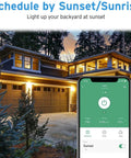 Smartphone app controlling Outdoor Two Socket Smart Plug WiFi Outlet With Alexa And Google Home Compatibility shown beside house at sunset