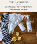 Cleaning products including Go-To All Purpose Surface Cleaner No 247 Scent with lemons and cloth on wooden table.