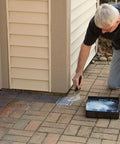 Man applying Premium Patio Paver Sealer Low Gloss Water Based Clear Stone Sealant to pavers near a house.
