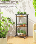 Slick Industrial 3 Tier Bar Cart With Smooth Rolling Wheels Antiqued Wood And Steel Liquor Cabinet For Home Bar Setup Serving Station And Kick Back Storage Rack with potted plants.