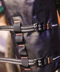 Close-up of a black Outpost Cargo Water Bottle Cage with triple mount holes and straps securing gear on a bike frame.