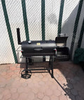 Outdoor view of an offset smoker grill featuring lid clamp replacement for Longhorn and Highland smokers with an open firebox.