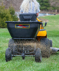 Rear view of Deluxe Tow Behind Broadcast Spreader With Extended Easy Reach Handle And Weatherproof Cover, 175 lb capacity in use