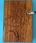 Dremel-style rotary tool with carbide burr carving a floral design into a wooden plaque.