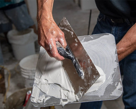 Flex Drywall Curved Trowel 12-Inch By 4.75-Inch With 0.5mm Blade spreading plaster on construction site