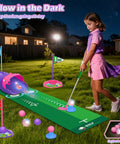 Child playing with Kids Golf Toy Set With Dinosaur Automatic Ball Return LED Light Up Night Balls 3 Clubs Putting Mat
