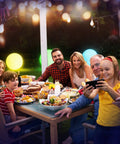 Family enjoying dinner outdoors with 16 Inch Light Up Glow Beach Ball With 8 LED Modes For Night Pool Fun, glowing in the background.