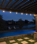 Backyard Bistro Style 24 Foot Outdoor String Lights illuminating a pergola by a pool at night, 12 shatter-resistant bulbs visible