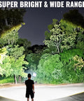 Person using Rechargeable Spotlight 2,000,000 Lumen Handheld Searchlight With Foldable Tripod lighting up trees at night.