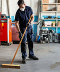Man using Heavy Duty 18 Inch Palmyra Bristle Push Broom For Garage Indoor Floor Sweep on concrete floor.