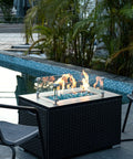 Poolside gas fire pit with Caribbean Blue 20 Pound 1 Inch Fire Glass Diamonds For Gas Fire Pit And Fireplace, flames glowing.