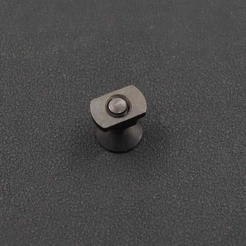 Black M-LOK M5 screw and T-nut hardware component on dark textured surface, front view