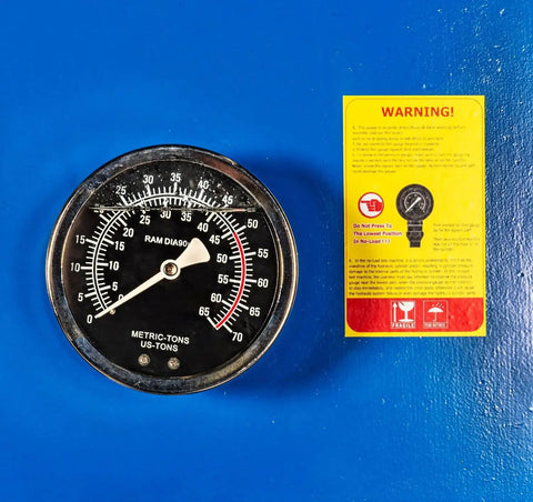 Close-up of pressure gauge on 50-Ton Hydraulic Shop Press With Floor Mount, Air Operated Foot Pedal Or Manual Operation next to warning label.