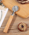 Pastry wheel cutter with wooden handle and fluted metal wheel on wooden cutting board