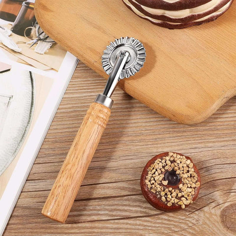 Pastry wheel cutter with wooden handle and fluted metal wheel on wooden cutting board
