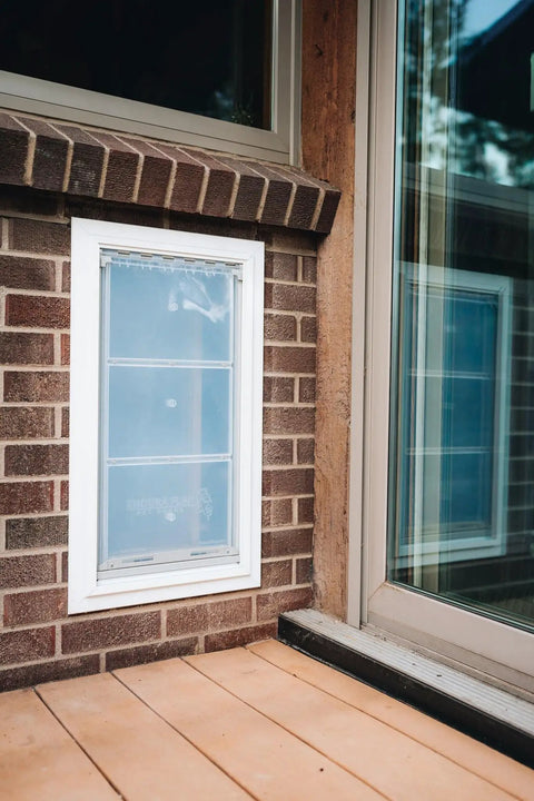 Premium Wall Mount Pet Door In White XL with double flap design mounted in brick wall for reliable pet access.