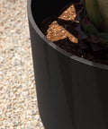 Close-up view of round black plastic planter pots with drainage holes for indoor outdoor use, durable plastic stone composite planters weatherproof.