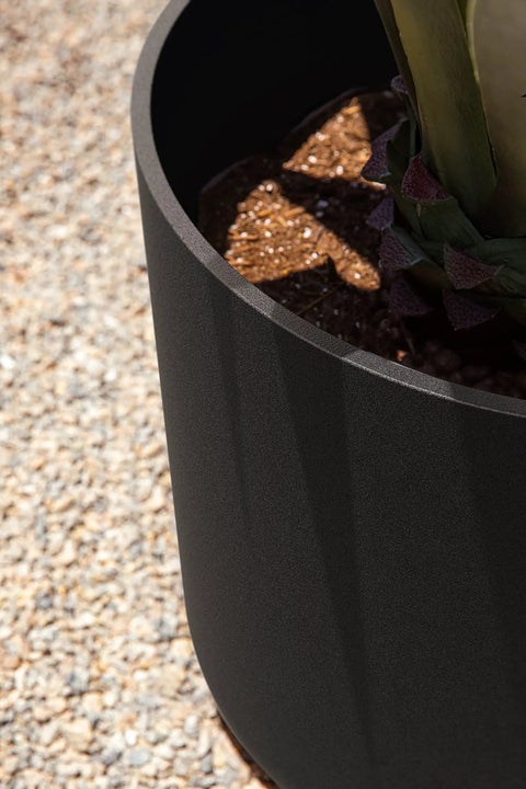 Close-up view of round black plastic planter pots with drainage holes for indoor outdoor use, durable plastic stone composite planters weatherproof.