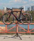 Heavy Duty Bike Repair Stand For Home Shop And Pro Mechanics Adjustable Bicycle Workstand holding road bike outside