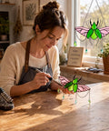 Woman assembling a stag beetle suncatcher from the Stag Beetle Stained Glass Kit for beginners on a wooden table.