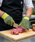 Yellow Medium Kevlar Knit Cut Resistant Work Gloves For Tough Jobs ANSI Rated Hand Protection From Glass Sheet Metal And Sharp Objects Heavy Duty Safety Gear You Can Trust being used by a person cutting meat in a kitchen.
