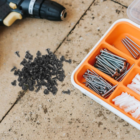 One Hundred Pack M4x10mm Black Carbon Steel Miniature Wood Screws scattered on a work surface with a toolbox.