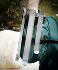 Close-up of medieval bracers for cosplay and reenactments, fully functional arm guards with splinted steel, worn by person in green tunic.