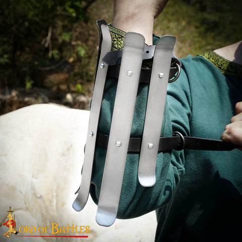 Close-up of medieval bracers for cosplay and reenactments, fully functional arm guards with splinted steel, worn by person in green tunic.