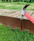 DIY Friendly 20Ft Plastic Garden Edging Kit With 25 Stakes Four Point Five Inch Tall Lawn Border being installed with hammer
