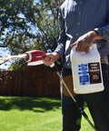 Person applying Liquid Sea Kelp And Humic Acid Blend For Grass And Plants That Boosts Your Lawn Game Seaweed Rich Soil Conditioner