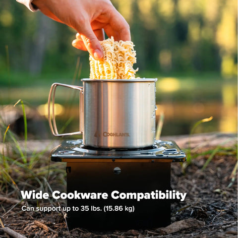 Portable Folding Camp Stove For Camping And Backpacking with cookware, supports 35 lbs, on forest ground