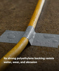 Extra Heavy Duty Duct Tape 6969, Silver, used on a yellow pipe, showcasing water resistance and abrasion resistance on concrete.