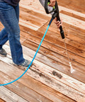 Pressure washer nozzle tips with blue 1/4-inch quick-connect hose; side view on wooden deck.
