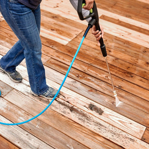 Pressure washer nozzle tips with blue 1/4-inch quick-connect hose; side view on wooden deck.