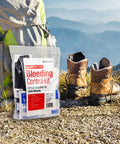 First Aid Only Right Response Bleeding Control Kit for limb wounds, 7 pieces, white pouch, outdoor scene with boots.